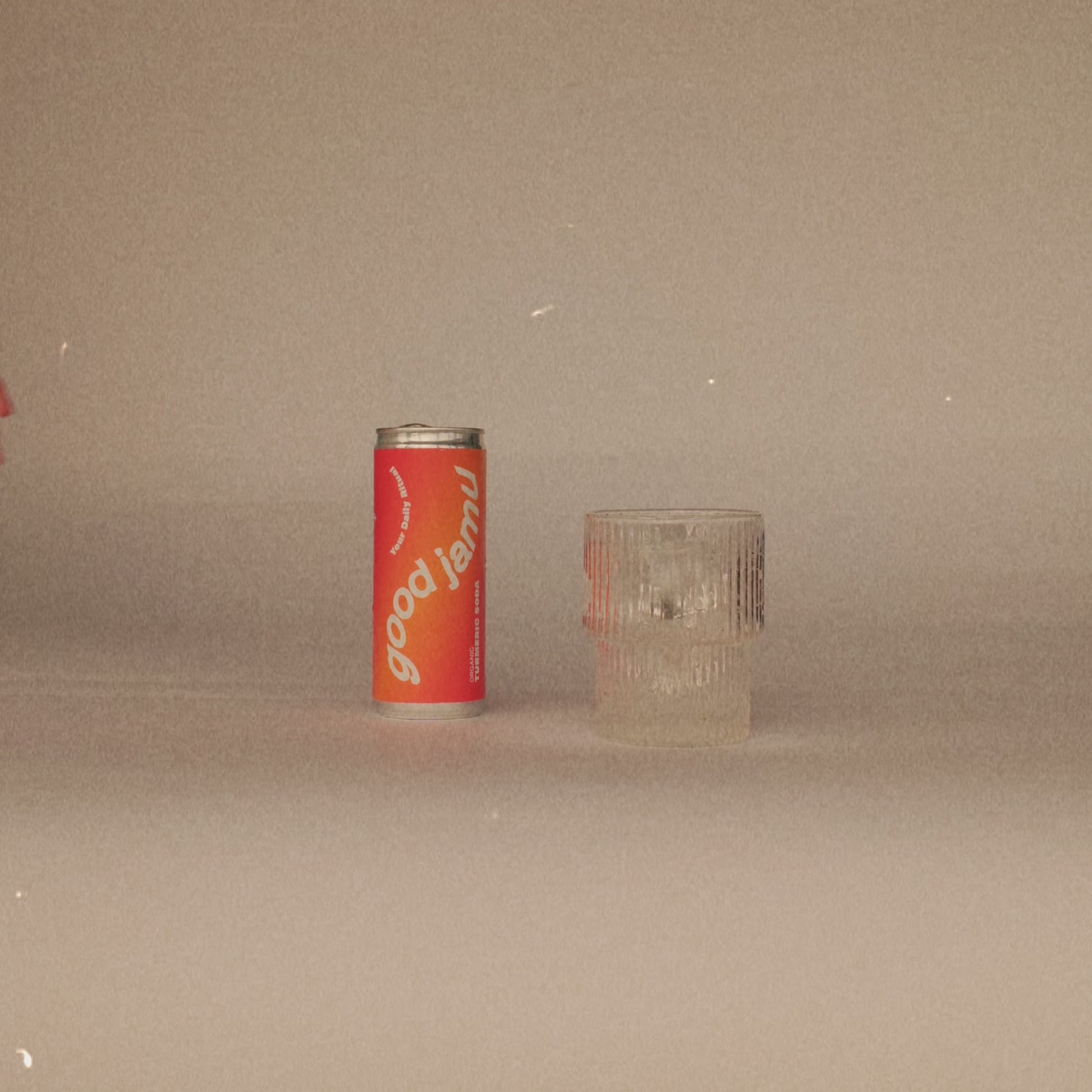Oranje Good Jamu soda uit Starterpack naast glas. Verfrissende drank met natuurlijke ingrediënten en Jamu-inspiratie.